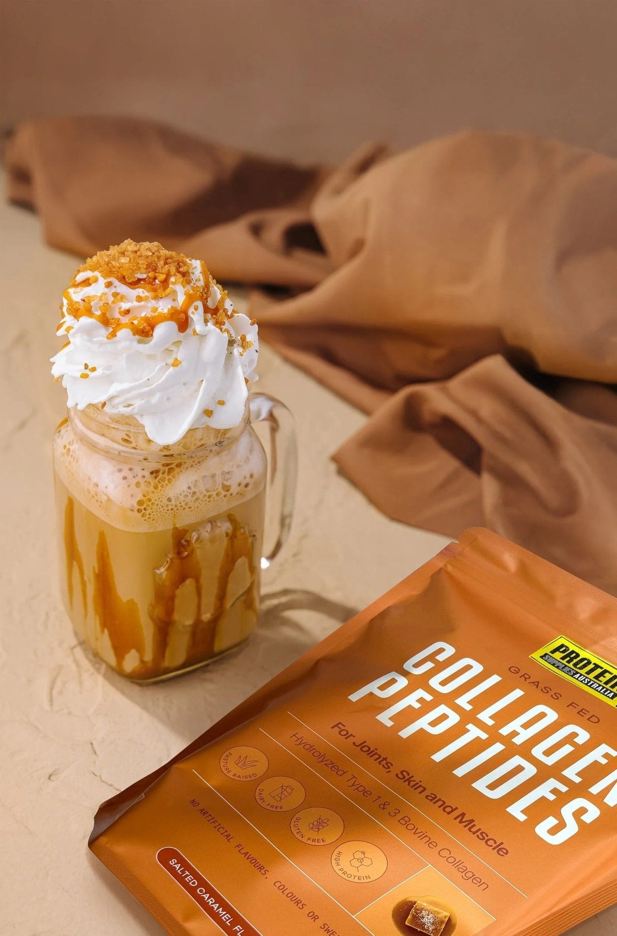 Glass mug with whipped cream and caramel next to Grass Fed Collagen Peptides - Salted Caramel - 1kg by Protein Supplies Australia