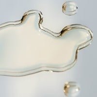 Close-up of clear liquid drops on a white surface representing Tuttofare Cleansing Oil - 100ml from Body & Beauty collection.