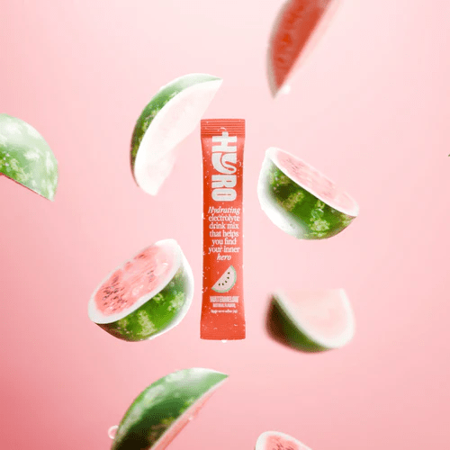 Hyro Single Stick watermelon electrolyte drink mix surrounded by watermelon slices on a pink background