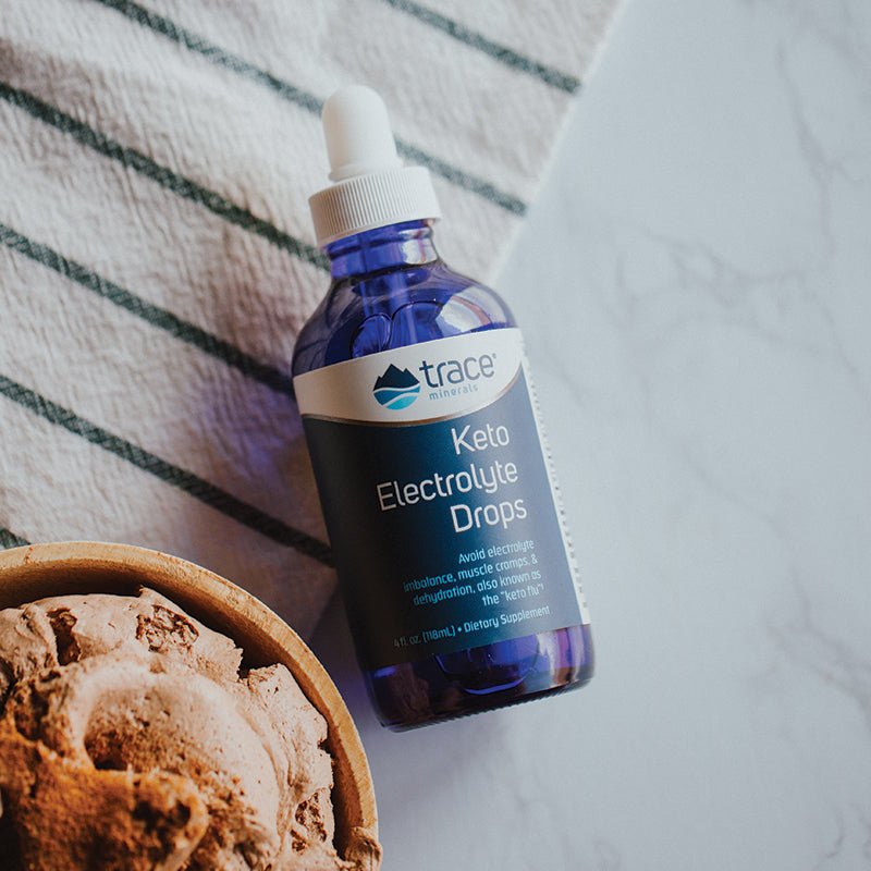 Keto Electrolyte Drops -118ml bottle by Trace Minerals with dropper cap beside a bowl of food on marble surface