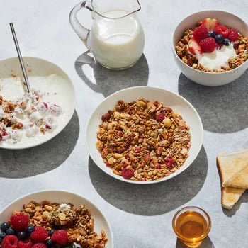 KETO Raspberry, Macadamia, and Vanilla - 300g by Blue Frog served in bowls with milk, berries, toast, and honey on table.
