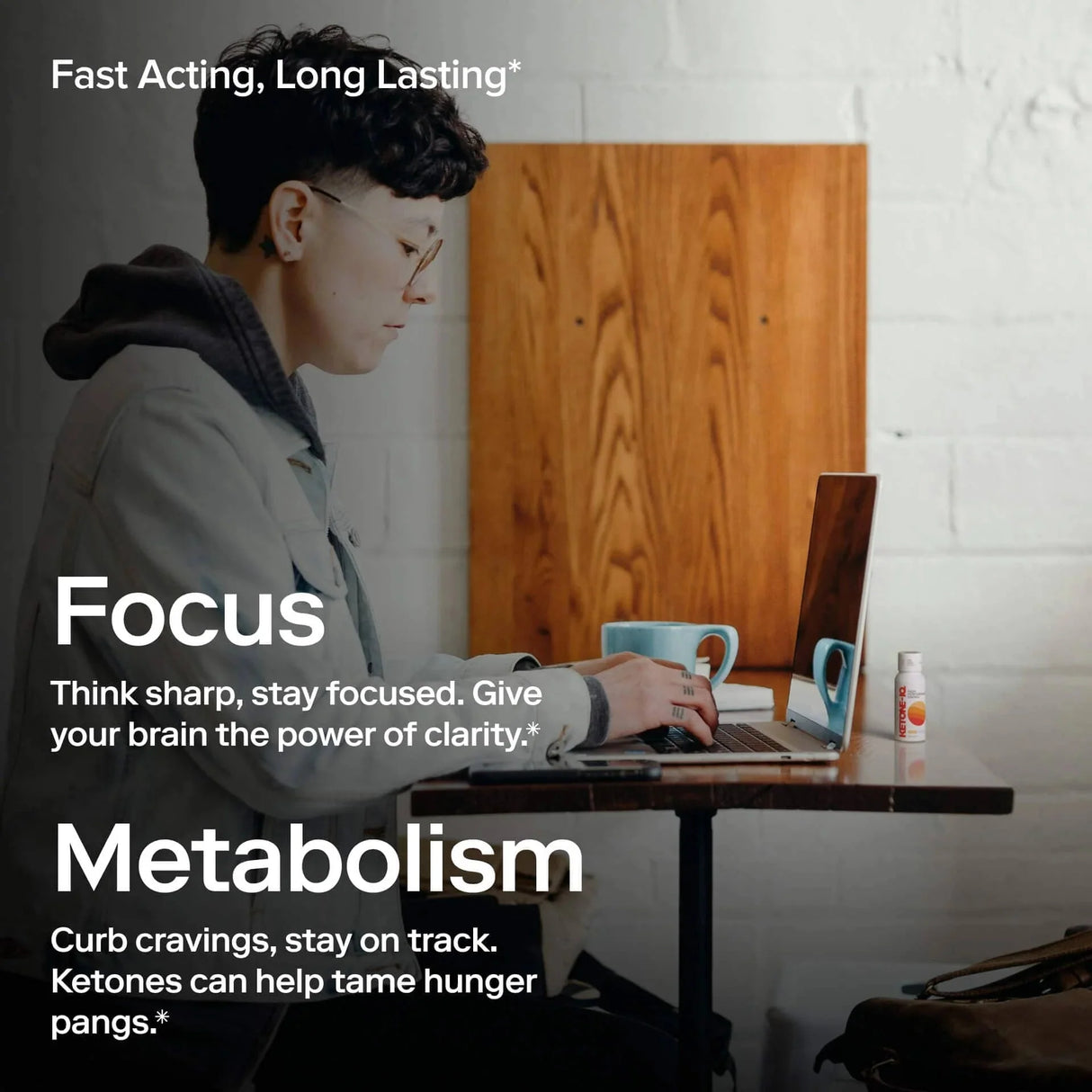 Person working on laptop with mug and Ketone-IQ - Energy Shot - Green Apple - 59ml x 6 - Best Before 28 Jul 2026 nearby, promoting focus and metabolism benefits.