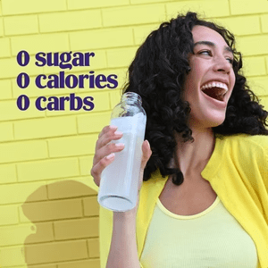 Woman in yellow shirt smiling and holding a clear bottle with Lemonade Electrolyte Drink Mix - 90 Serves by Ultima Replenisher