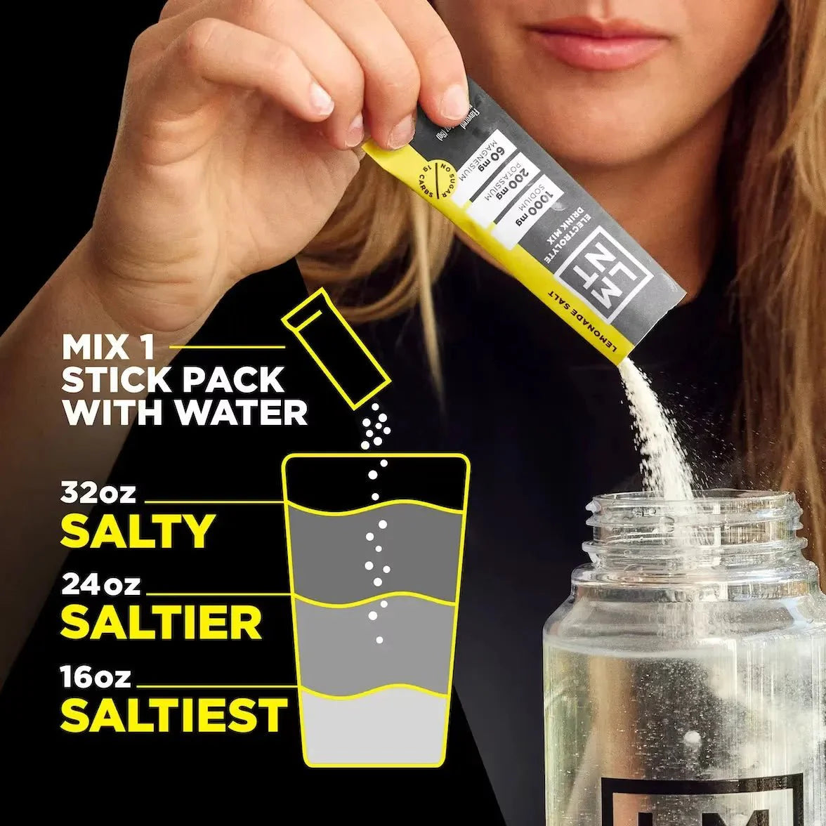 Person pouring LMNT Lemonade Salt Electrolyte Mix - 30 Sticks by LMNT into water bottle with instructions for mixing different salt intensities for keto hydration.