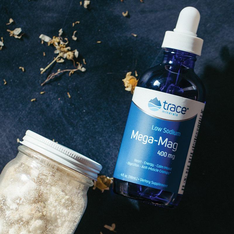 Low Sodium Mega-Mag - 400mg - 118ml by Trace Minerals in blue bottle with dropper on dark surface with jar and dried flowers
