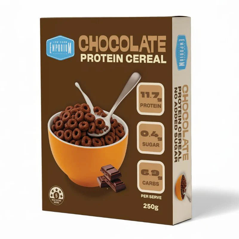 A brown box of Low Carb Emporium Protein Cereal - Chocolate Flavour (250g) shows a bowl of chocolate cereal, spoons, and chocolate squares. Each serve has 11.7g protein, 0.4g sugar, and 6.9g carbs for a low-sugar breakfast option.
