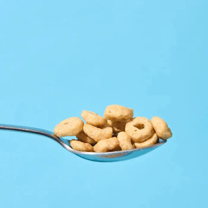 Close-up of a spoon holding Yo Keto Protein Cereal - Cinnamon Flavour - 250g by Low Carb Emporium on a blue background