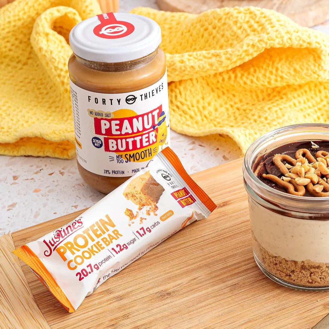 Protein Cookie Bar - Forty Thieves Peanut Butter - 60g with peanut butter jar and peanut butter dessert on wooden board