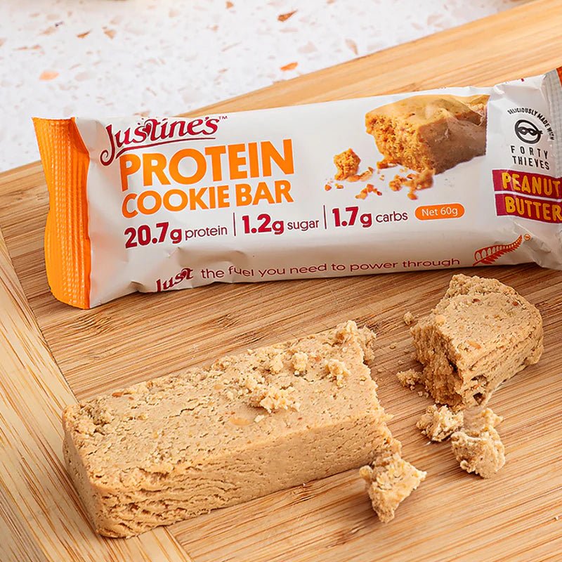 Protein Cookie Bar - Forty Thieves Peanut Butter - 60g by Justine's on wooden board with bar broken into pieces