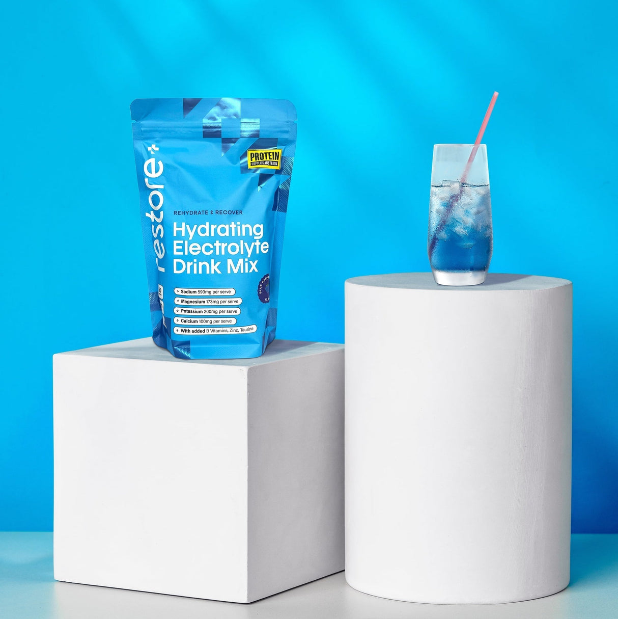 Restore Electrolyte Drink Mix Blue Raspberry 240g pouch with blue raspberry drink on white pedestals, bright background