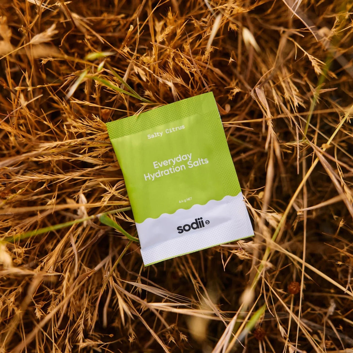 Salty Citrus - 30 Sachets by Sodii, Everyday Hydration Salts in bright green sachet on dry grass background