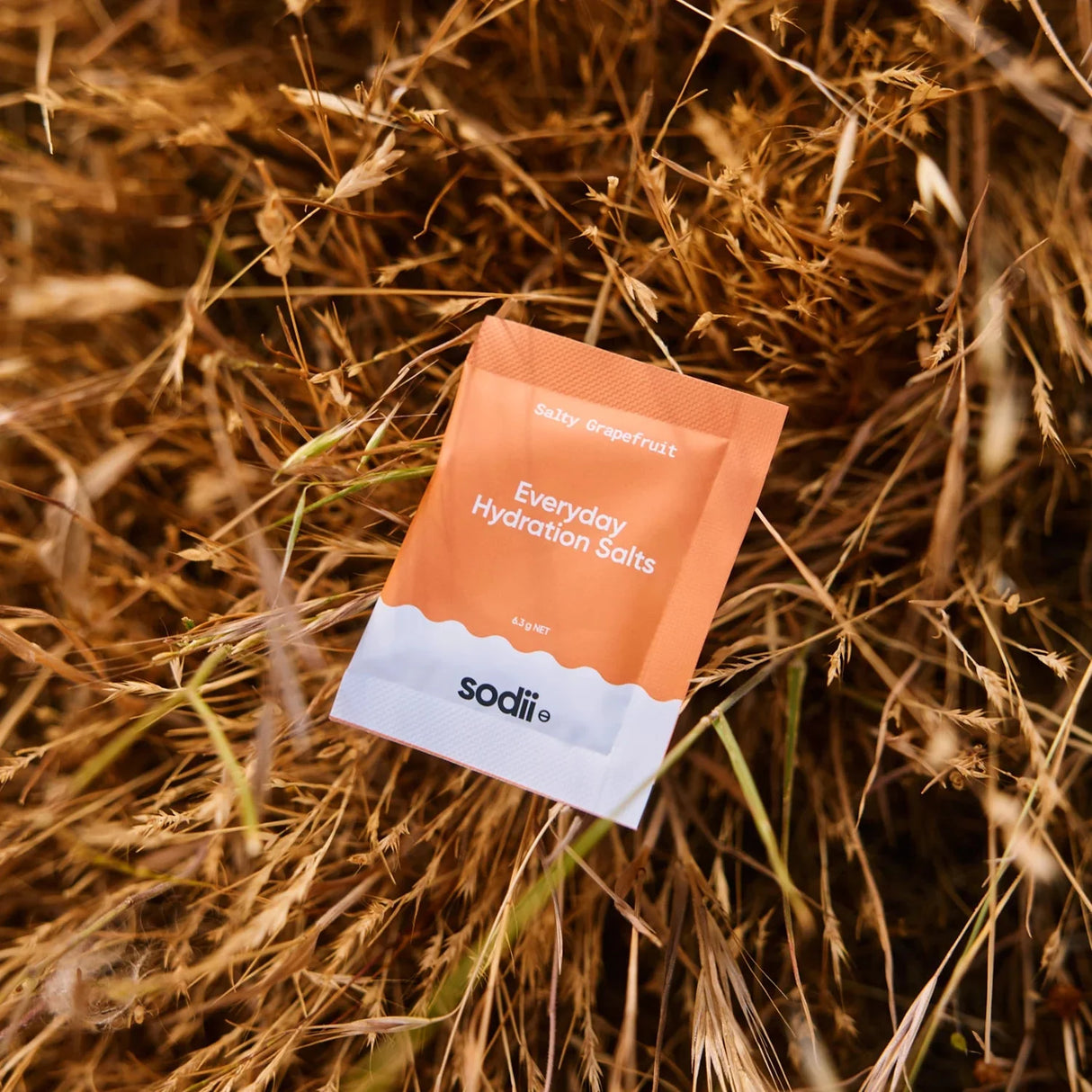 Salty Grapefruit - 30 Sachets by Sodii, Everyday Hydration Salts in orange-white sachet on dried grass background