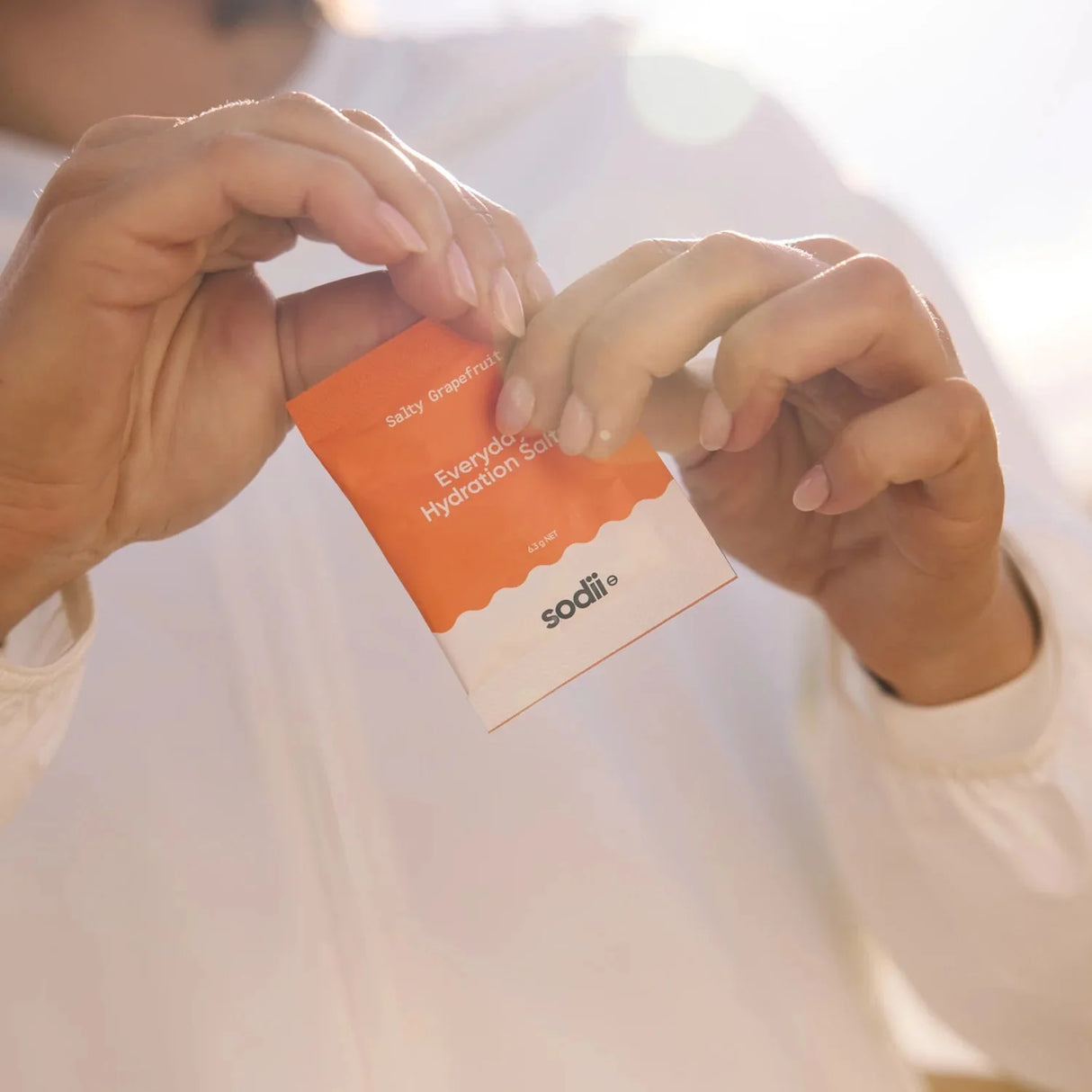 Person holding a sachet of Salty Grapefruit - 30 Sachets by Sodii from the Electrolytes and Drinks collections.