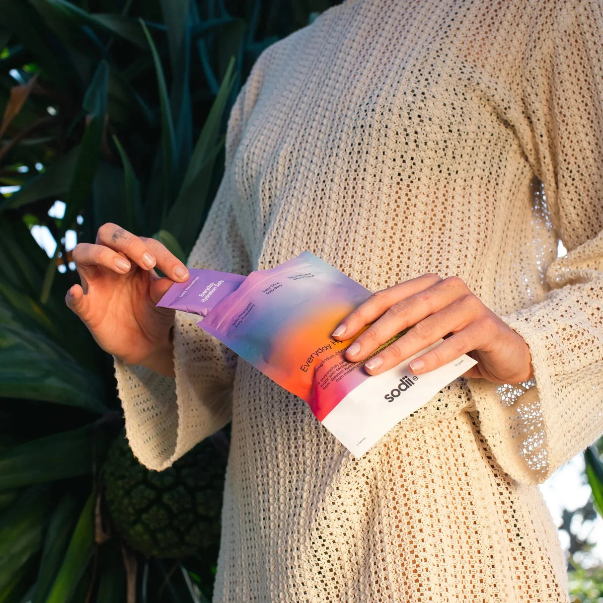 Person in knit sweater opening Salty Variety Pack - 8 Sachets by Sodii from the Electrolytes and Low Carb collections