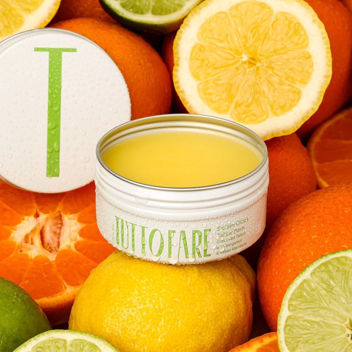 Open tin of Sicillian Citrus Tallow Balm - 70g by Tuttofare surrounded by sliced citrus fruits for skincare collection