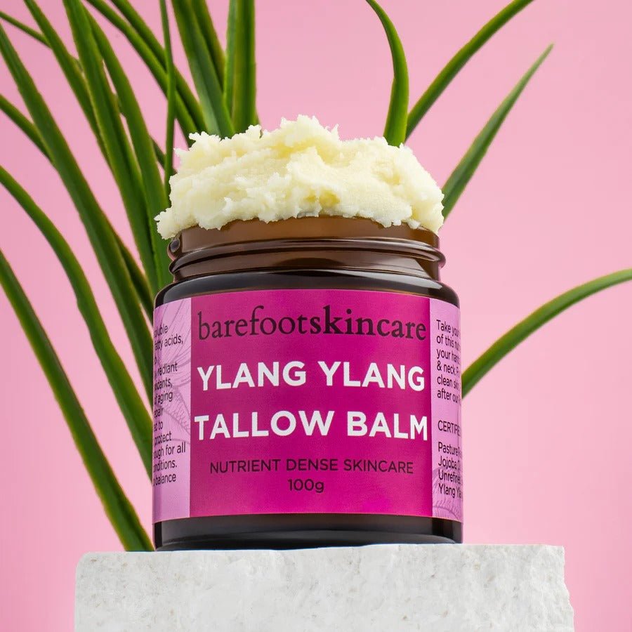 Tallow Balm - Ylang Ylang - 100g jar by Barefoot Skincare Co with creamy balm and green plant on pink background