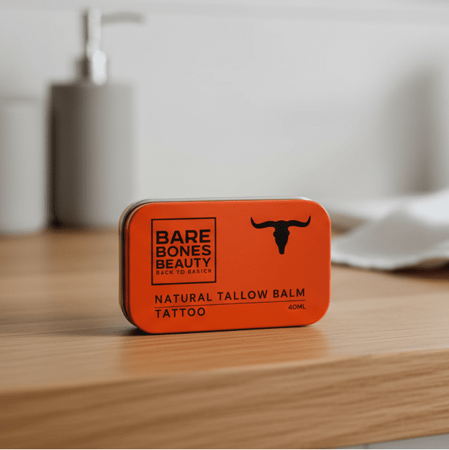 Tattoo Tallow Balm - 40ml by Bare Bones Beauty in an orange metal tin on a wooden surface with blurred background.