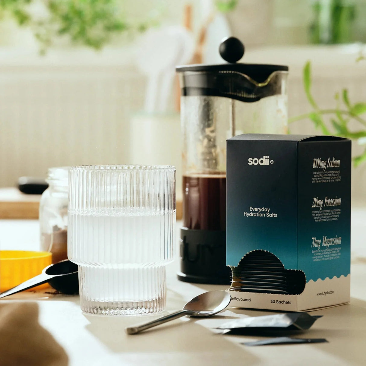 Unflavoured - 30 Sachets by Sodii alongside a glass of water, a French press, and spoons on a kitchen counter.