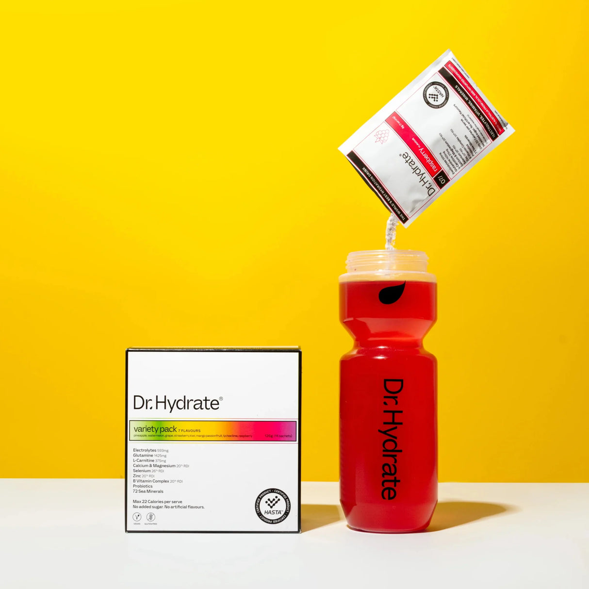 Dr. Hydrate Variety Sachet Pack - 14 Serves being poured into a red bottle against a bright yellow backdrop