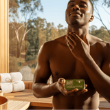 Dark-skinned man applying Aftershave Tallow Balm in sauna setting