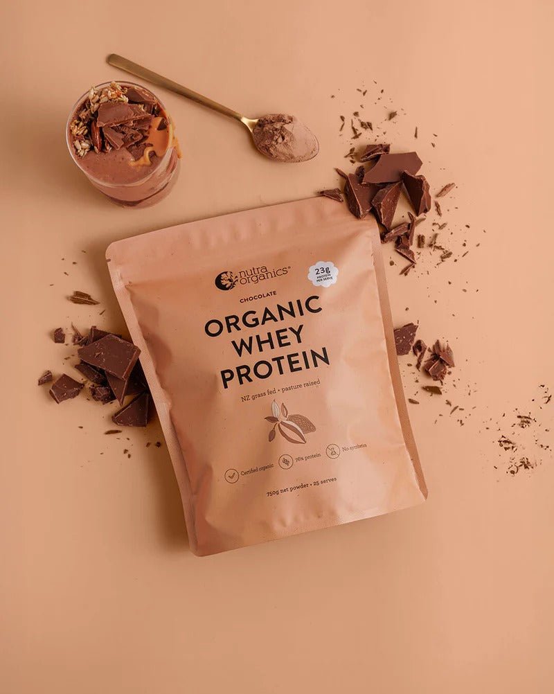 Nutra Organics Organic Whey Protein - Chocolate - 750g pouch with chocolate pieces and powder on beige background