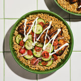 Bowl of Kaizen Protein Rice topped with grilled chicken, cucumber and tomato salad